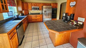 Ett kök med träskåp, ett kylskåp i rostfritt stål, en mikrovågsugn och en plats för att göra kaffe.