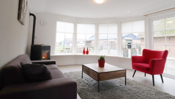 Ein modernes Wohnzimmer mit einer Couch, einem roten Sessel, einem Couchtisch und einem Kamin.