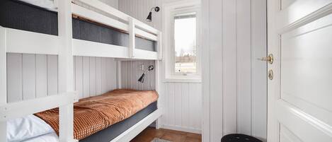 A bunk bed room with a window, a door, and a small stool.