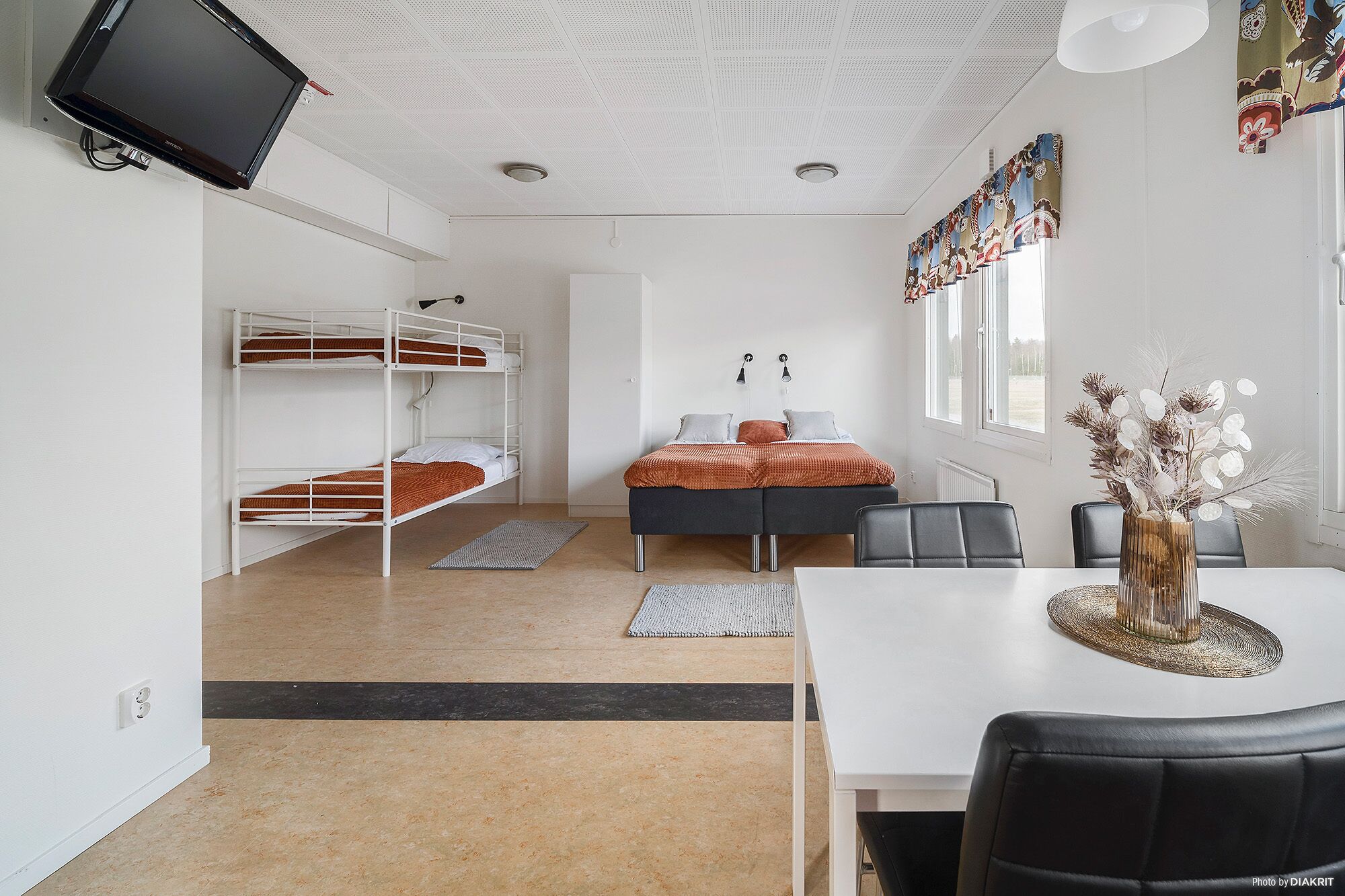 A dormitory room with bunk beds, a desk, a chair, and a dining table.