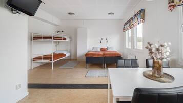 A dormitory room with bunk beds, a desk, a chair, and a dining table.