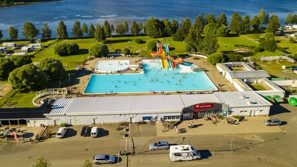 Vista aérea de un parque acuático con piscina, toboganes y un estacionamiento.