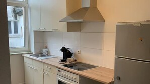 A compact kitchen with a built-in oven, a sink, and a stainless steel refrigerator.