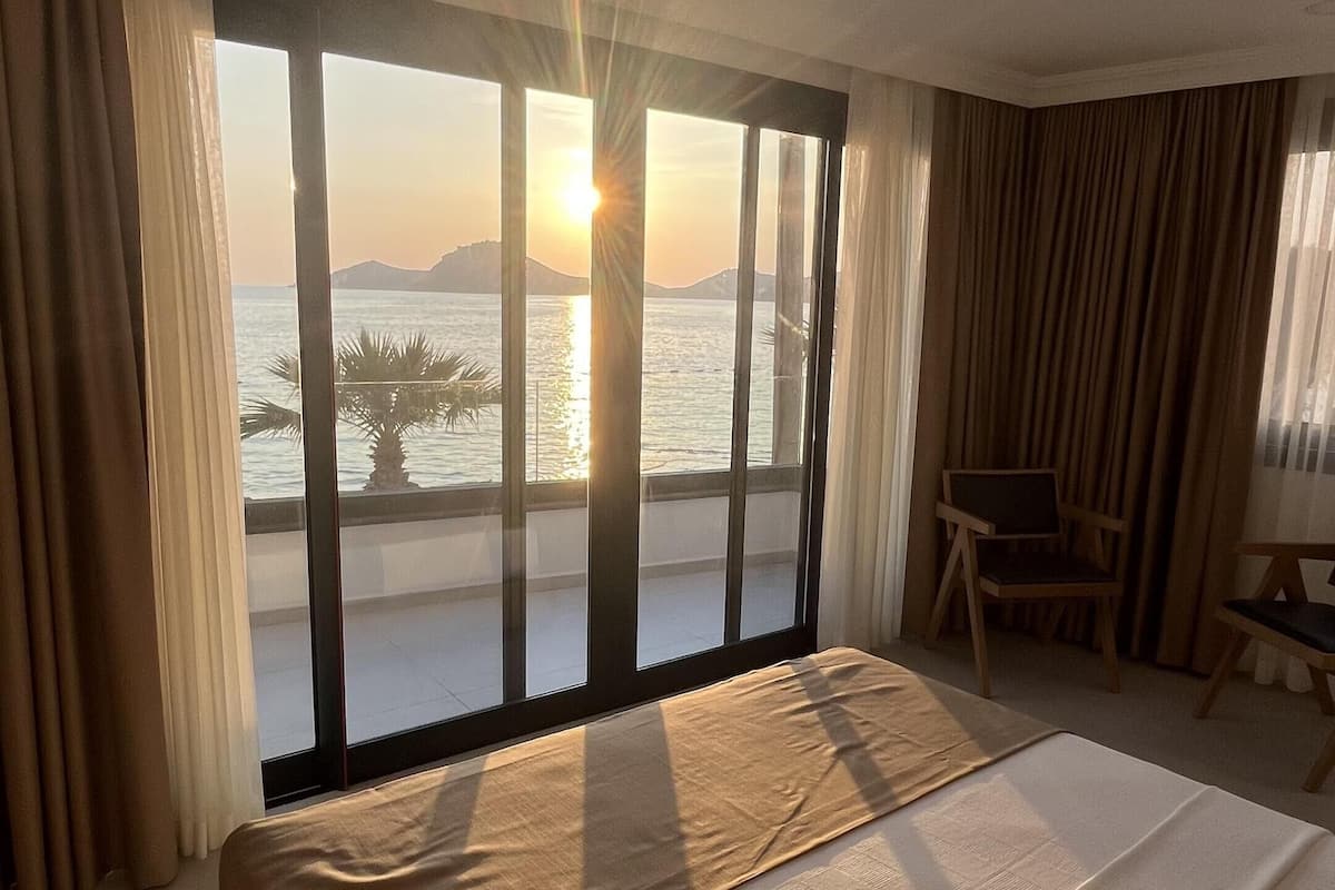 A bedroom with a large bed, a view of the sea, and a balcony.