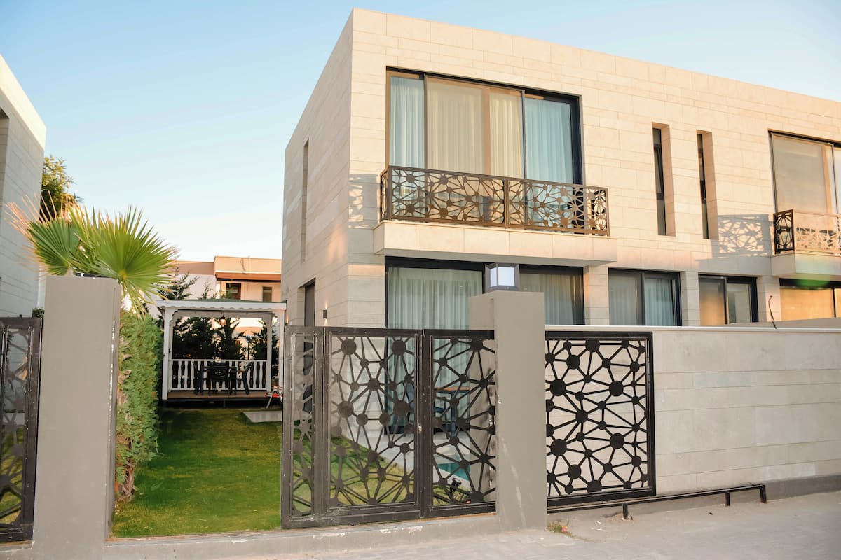 A modern building with a balcony, a gated entrance, and a small lawn area.