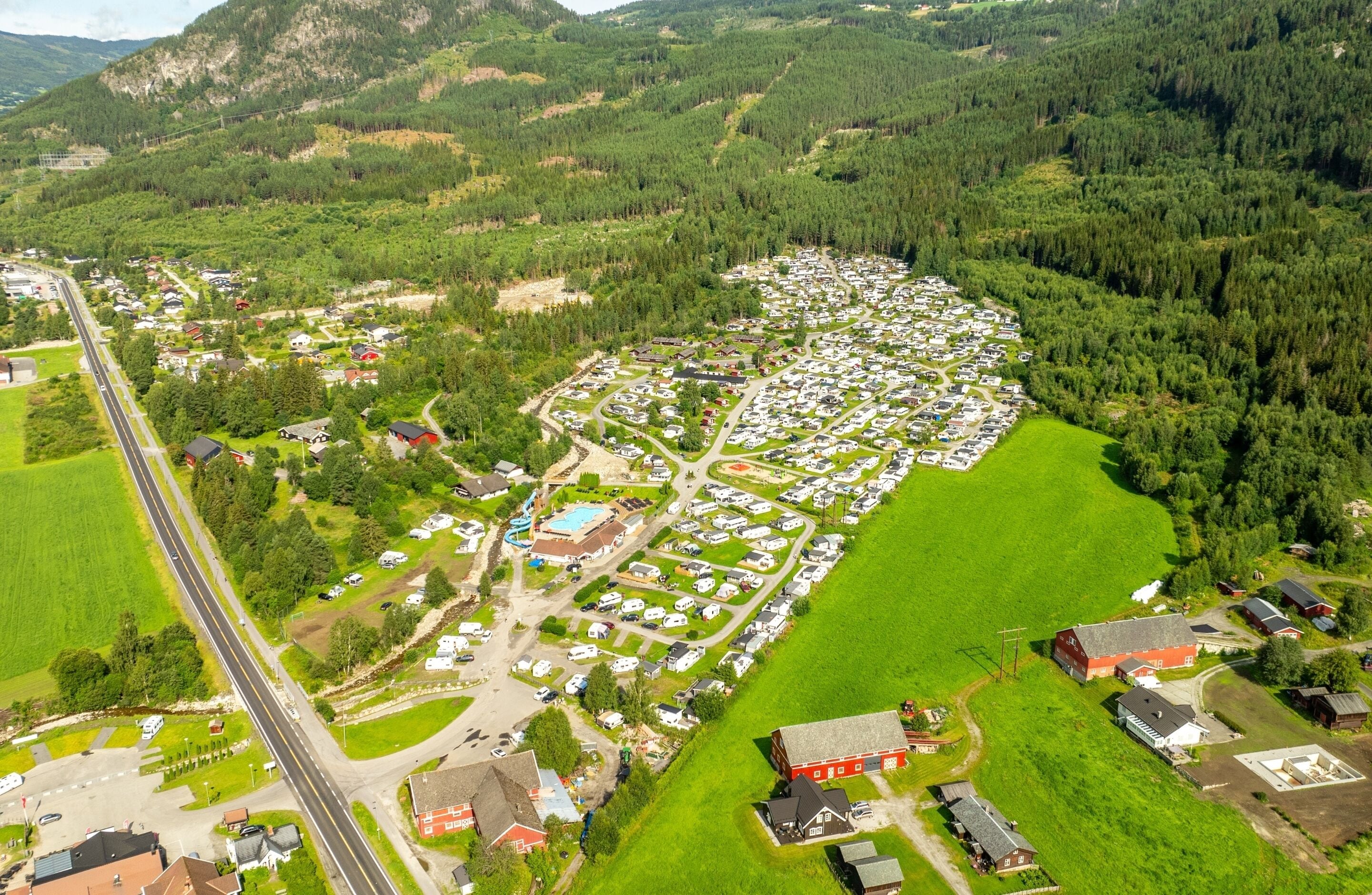 Ett flygbildsbild av ett bostadsområde med hus, en väg och omgivande grönska.