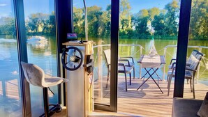 Interior moderno de barco con timón, una pequeña mesa y dos sillas.