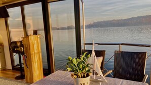 Una mesa con una planta y un modelo de barco en un balcón con vistas a un lago.