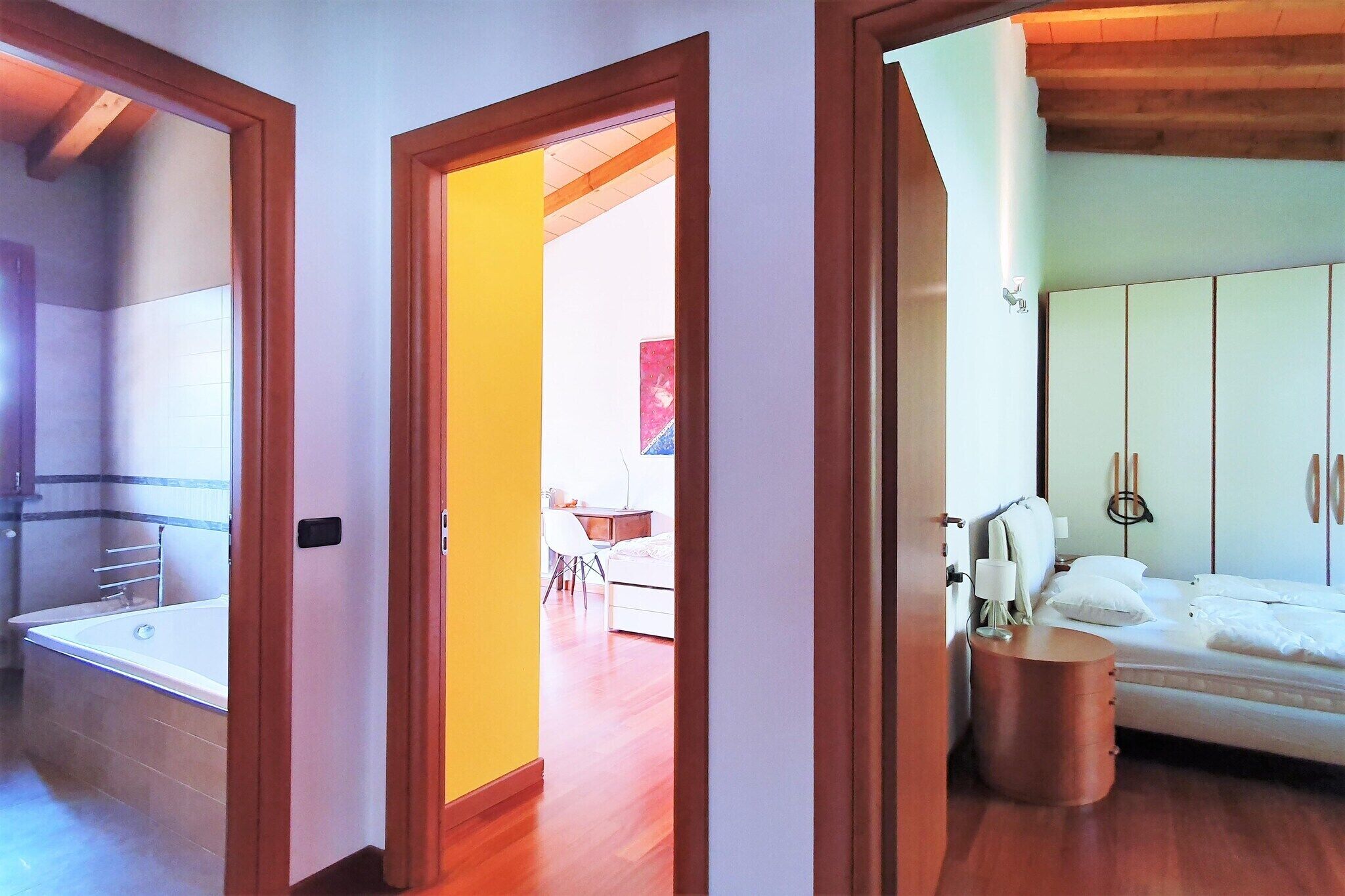 A bedroom with a bed, bedside table, and a wooden floor.