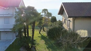 Et boligområde med udsigt til havet, med huse med tegltage, en velholdt græsplæne og palmer.