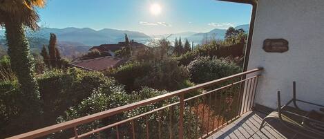 A balcony with a metal railing overlooking a mountainous landscape.
