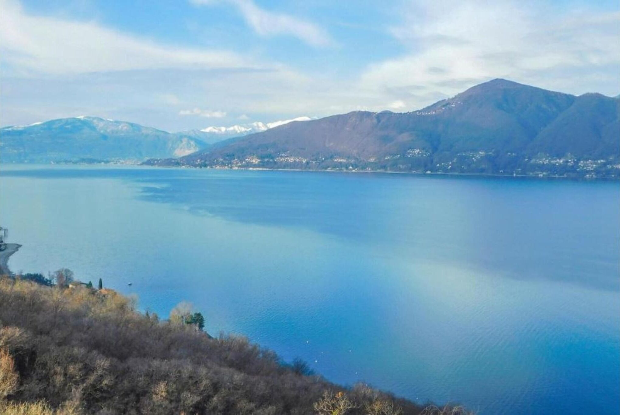 Un lac paisible, avec des montagnes en arrière-plan et un ciel dégagé.