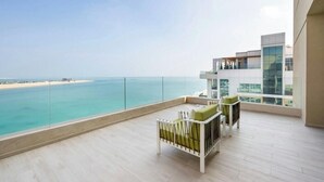 A balcony with a view of the sea, a modern building, and a white chair. - Agora, Doha, Autograph Collection (Lusail)