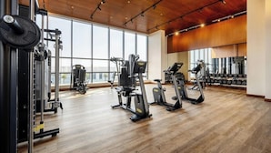 A gym with cardio machines, weightlifting equipment, and large windows. - Agora, Doha, Autograph Collection (Lusail)