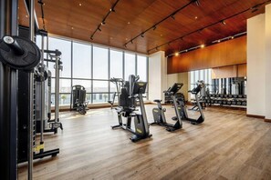 A gym with cardio machines, weightlifting equipment, and large windows. - Agora, Doha, Autograph Collection (Lusail)