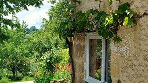 Un edificio rústico de piedra con una ventana y una pared cubierta de hiedra.