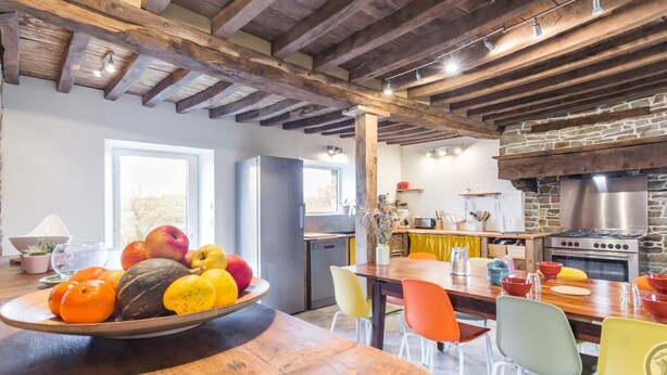 Una cocina rústica con vigas de madera a la vista, pared de piedra y una estufa grande.