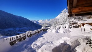 Un paisaje nevado de montaña con una cabaña de madera y una valla cubierta de nieve.