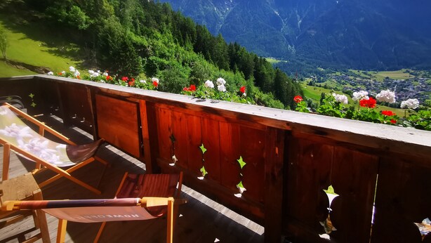 Una terraza de madera con vistas a una cadena montañosa y un valle abajo.