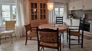 Un coin repas comprenant une table ronde, quatre chaises, un buffet en bois doté de portes en verre et un luminaire suspendu.