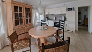 Une cuisine moderne avec des meubles blancs, une table ronde en bois et des chaises noires.