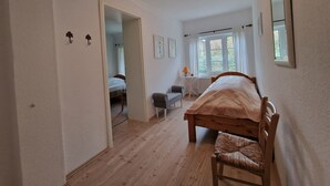 Une chambre à coucher avec un lit en bois, une chaise, un bureau et une fenêtre avec des rideaux.