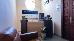 A reception area with a wooden reception desk, a digital clock, and a wall calendar. - DOWNTOWN HOTEL (Antananarivo)
