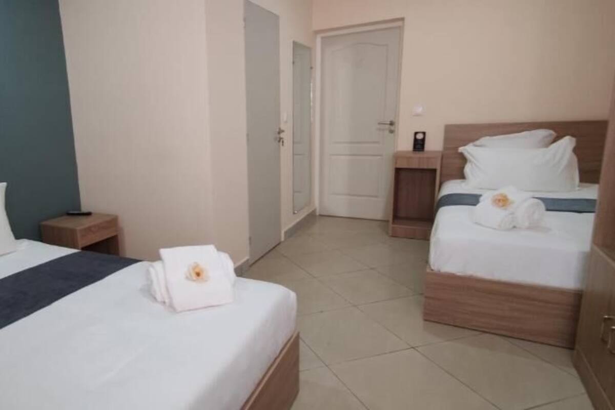 Een hotelkamer met twee bedden, een houten hoofdeinde, een nachtkastje en een badkamers deur.
