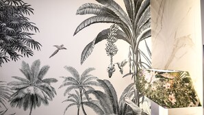 Pared con un mural detallado de plantas tropicales y un pájaro volando.
