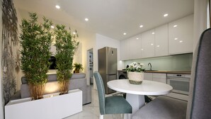 Una cocina moderna con armarios blancos, un refrigerador de acero inoxidable y una mesa de comedor redonda con dos sillas.