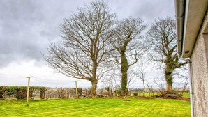 Een verzorgd gazon met volgroeide bomen en een stenen muur.