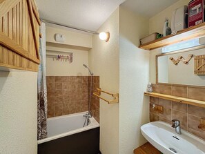 Een badkamer met een bad, wastafel, spiegel en handdoekrek.