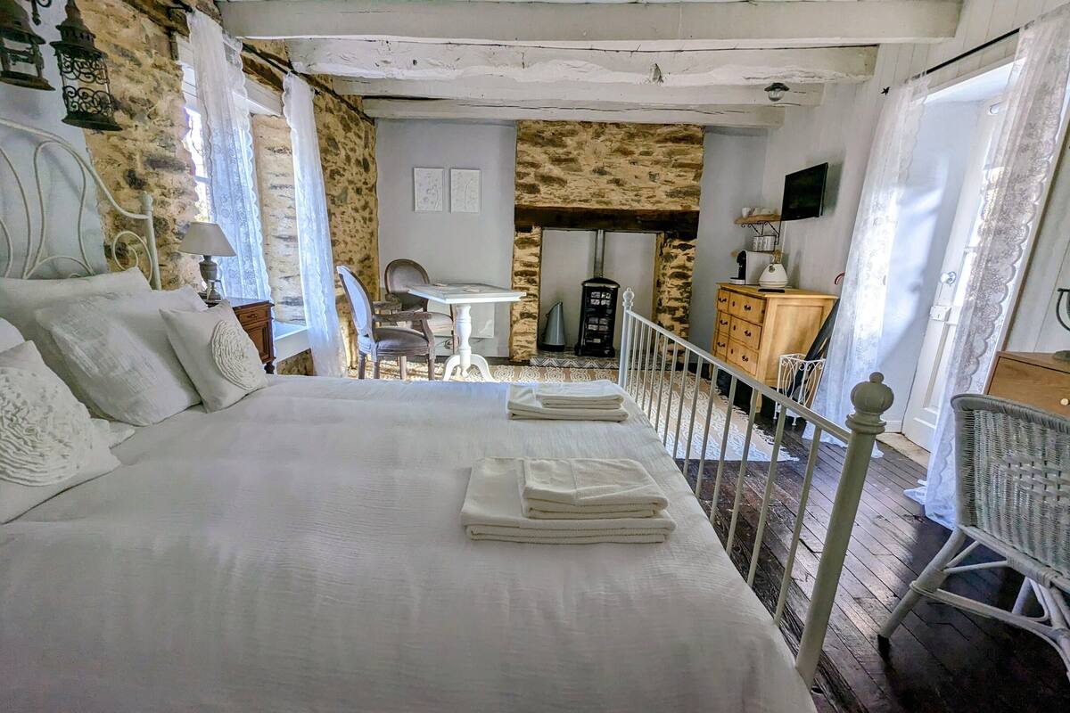 A bedroom with a large bed, a small table, and a chair.