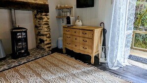 Een rustieke kamer met een stenen muur, een houten dressoir en een kamerbreed tapijt met dessin.