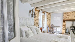 Een slaapkamer met een groot bed, een stenen muur, een houten plafond en een rustieke uitstraling.