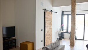 Ein modernes Wohnzimmer mit einer Schiebetür im Bauernhausstil, einem Flachbildfernseher, einer Couch und einem Couchtisch.