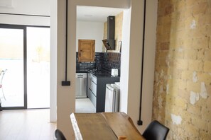 A modern kitchen with a wooden door, black tiled backsplash, and stainless steel appliances. - PR27 RUZAFA APARTMENT WITH 50 M TERRACE AND SMALL POOL (València)