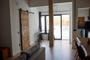 A spacious living area with a sliding barn door, a dining table, and a view to an outdoor patio. - PR27 RUZAFA APARTMENT WITH 50 M TERRACE AND SMALL POOL (València)