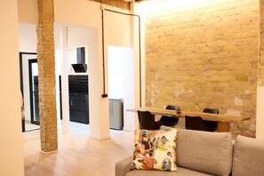 A modern living room with a brick wall, a wooden dining table, and a grey sofa. - PR27 RUZAFA APARTMENT WITH 50 M TERRACE AND SMALL POOL (València)