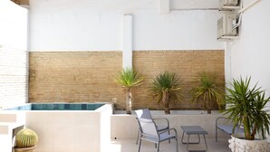 Eine Dachterrasse mit Pool, Sitzgelegenheit und Topfpflanzen.