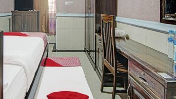 Ein Hotelzimmer mit zwei Betten, einem Holzkasten, einem Fernseher und einem Spiegel.