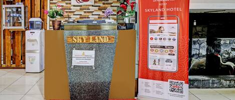 A reception desk with a wooden sign reading "SKYLAND HOTEL" and a red carpet in front.
