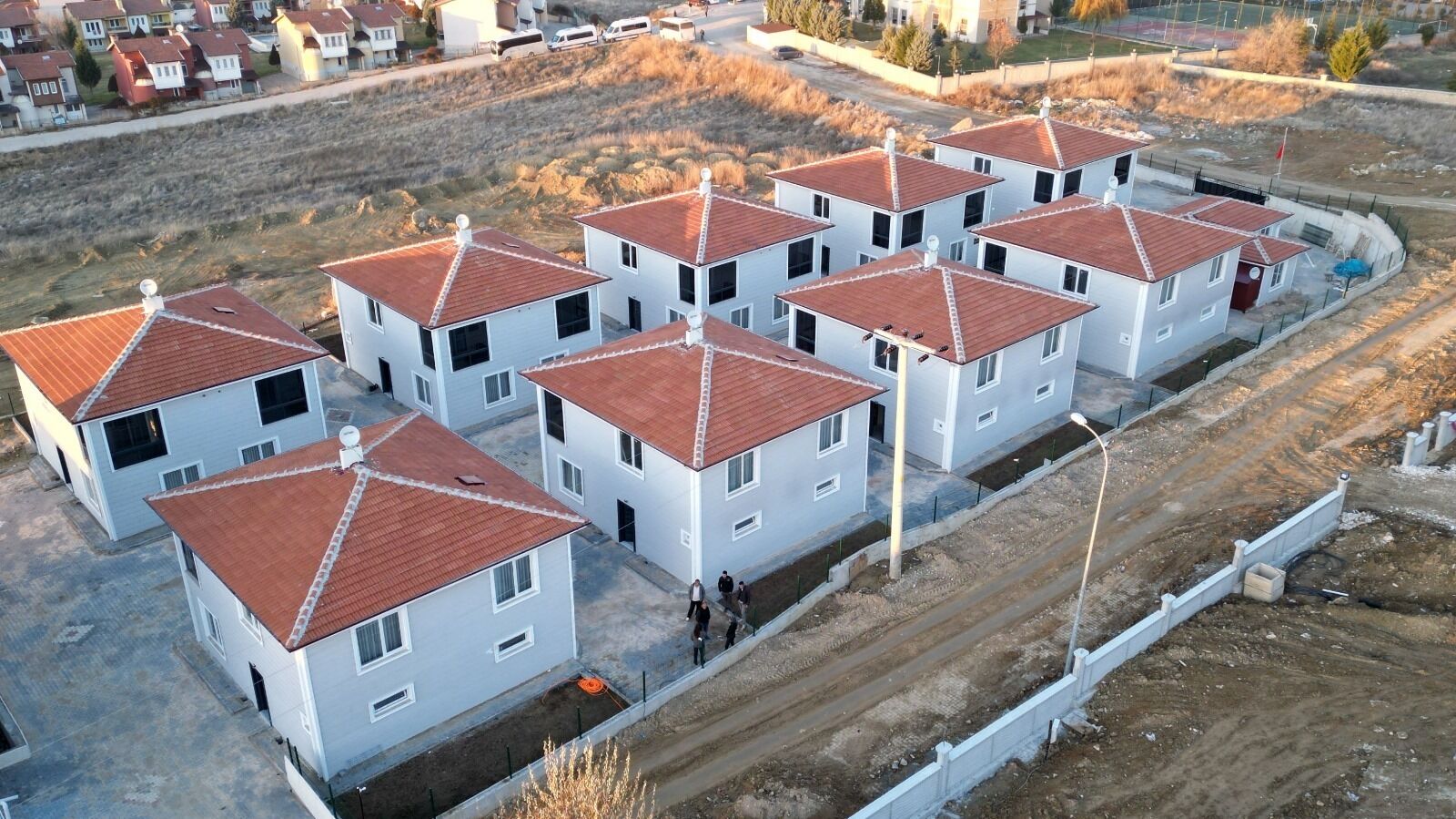 Una zona residencial con varias casas blancas con techos de tejas rojas, dispuestas en hilera.