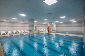 An indoor swimming pool with clear water, white lounge chairs, and a tiled ceiling with recessed lighting. - Regulus Termal Apart Hotel & Villas (Ihsaniye)