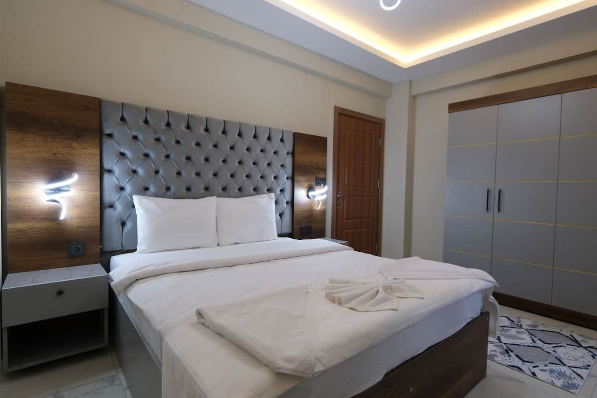 A modern bedroom with a tufted headboard, a large wardrobe, and a bedside table with a nightstand.