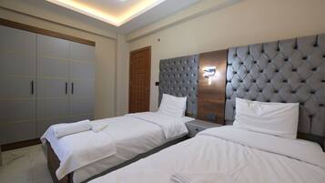 A hotel room with two beds, a large wardrobe, and a modern headboard.