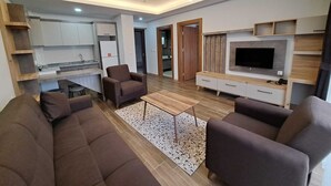 Een moderne woonkamer met een bank, een salontafel en een televisie bevestigd aan een houten wand.