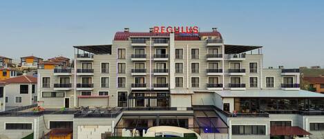 A multi-story hotel with balconies, a pool area, and a checkered outdoor seating area.