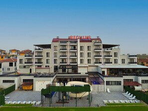 A multi-story hotel with balconies, a pool area, and a checkered outdoor seating area. - Regulus Termal Apart Hotel & Villas (Ihsaniye)