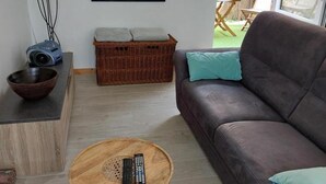 A living room with a sofa, a coffee table, a basket, a framed artwork, and a projector on a stand. - Terraced house in Barfleur with private courtyard - Pets allowed (Barfleur)